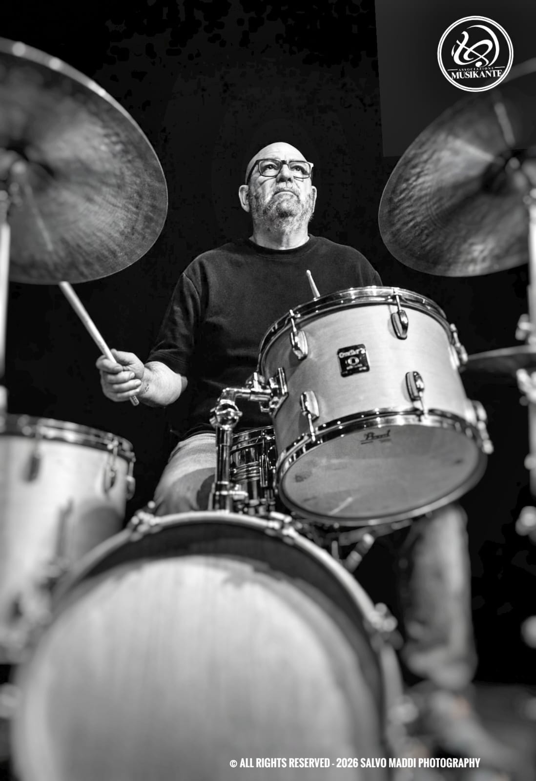 Antonio Petralia alla batteria durante un concerto, fotografato in bianco e nero